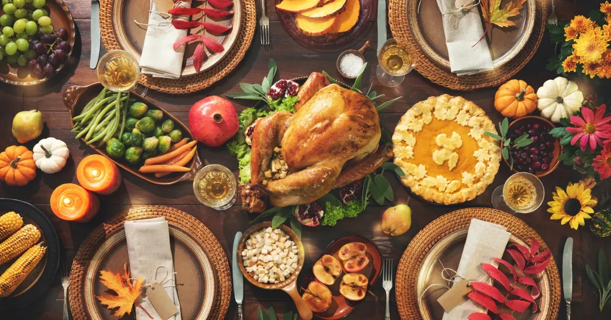 Overhead view of a complete holiday dinner spread with a golden roasted turkey, pumpkin pie, and side dishes